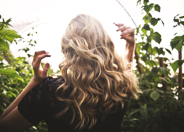 blonde haired woman in black top surrounded by tall plants