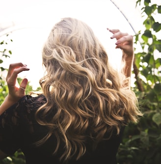 blonde haired woman in black top surrounded by tall plants