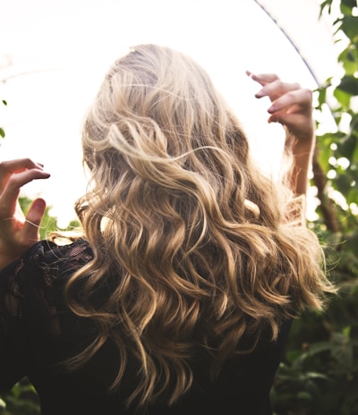 blonde haired woman in black top surrounded by tall plants