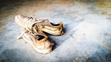 A pair of worn-out running shoes resting on a gym floor, symbolizing hard work.