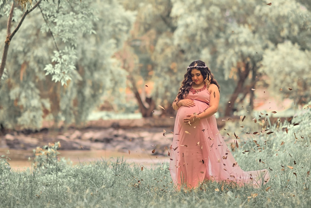 나무 근처에서 임신한 배를 안고 있는 여자