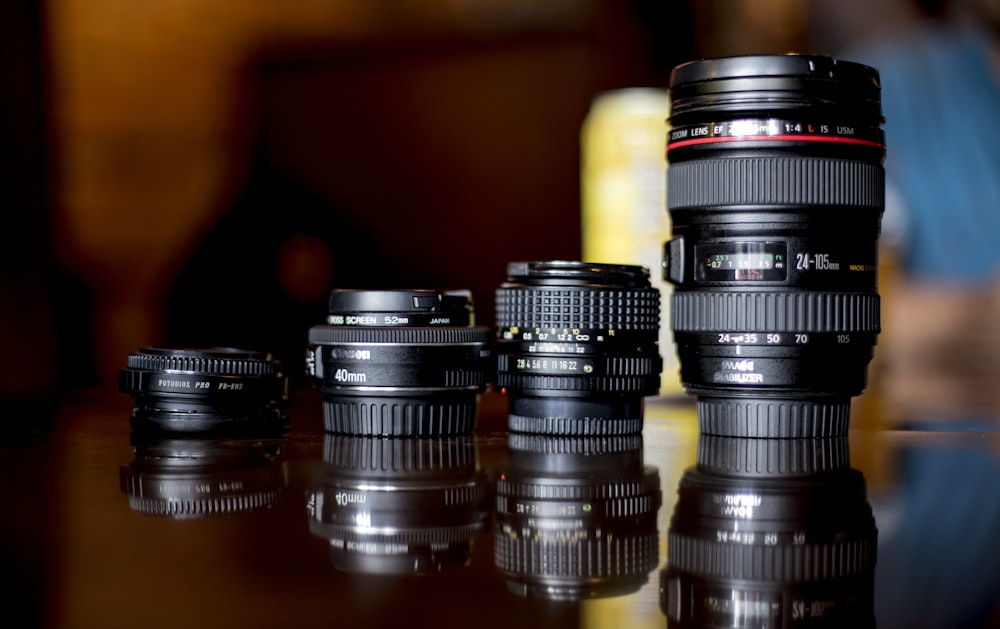 selective focus photography of four black DSLR camera lens on brown wooden surface