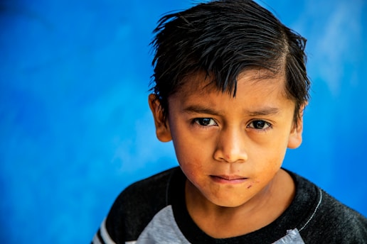 photo of boy standing against blue background