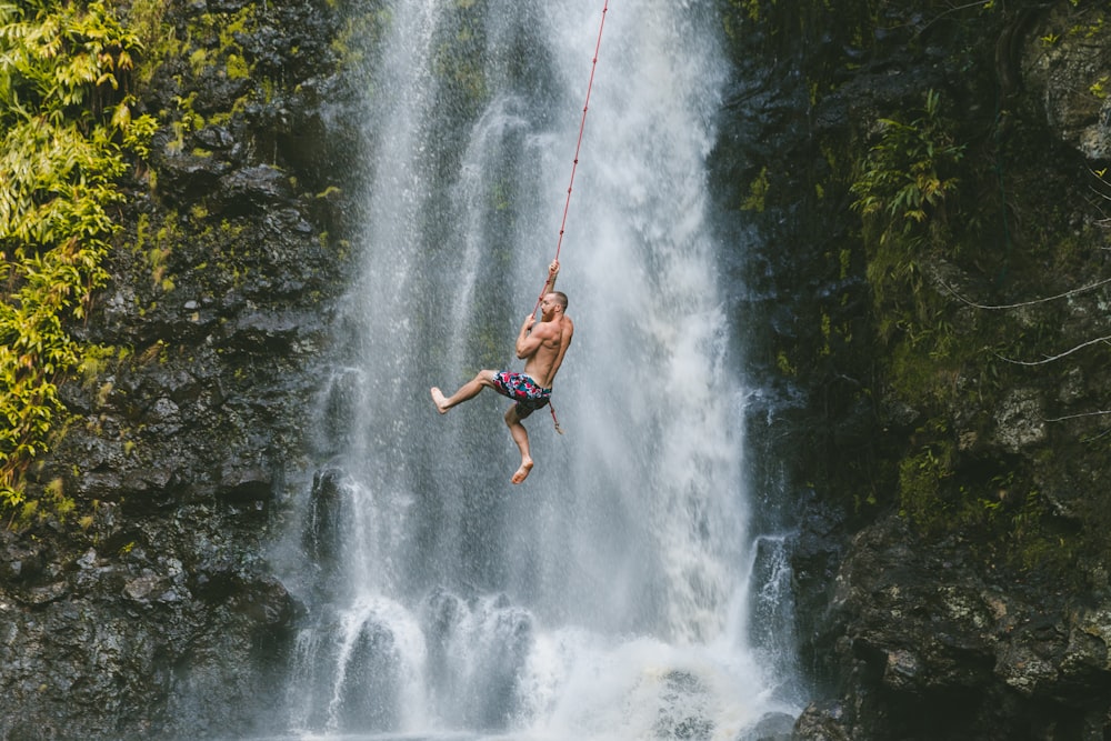 昼間、滝の近くでロープにぶら下がっている男性
