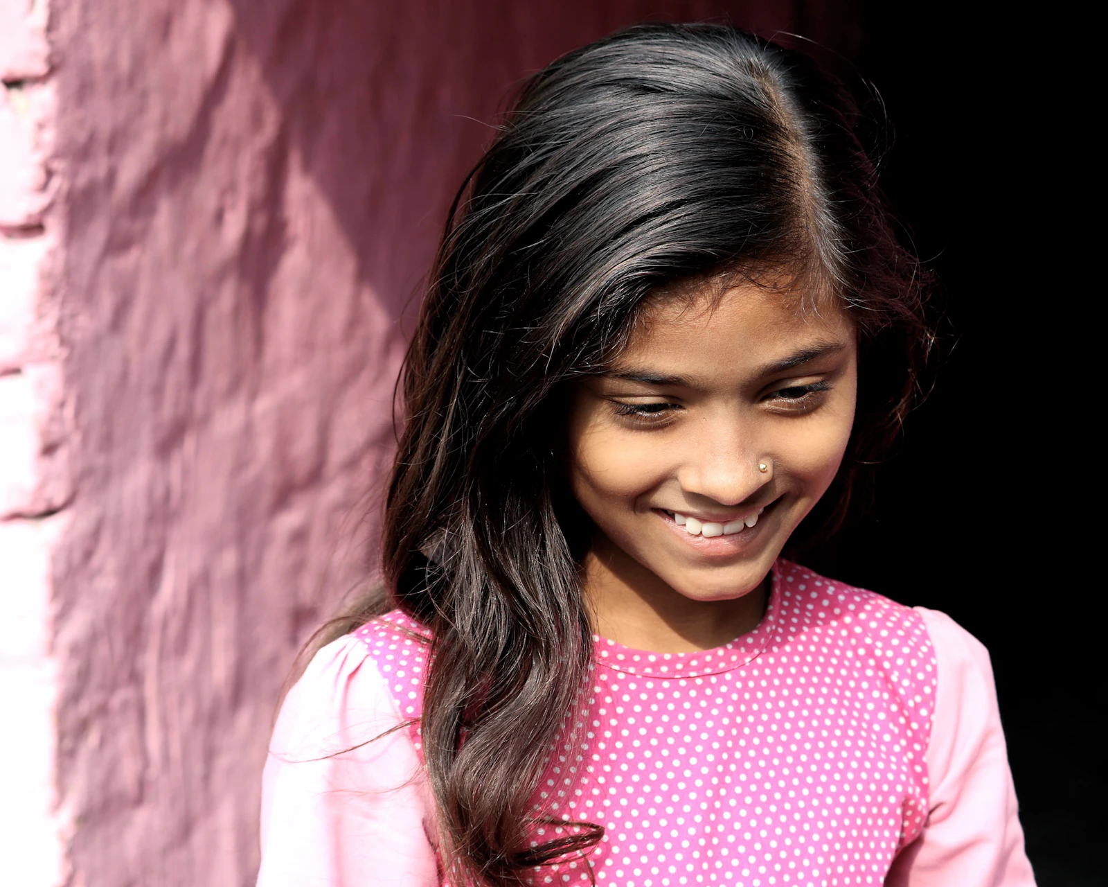 A smiling girl standing near a painted wall