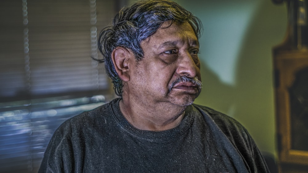 man standing near window blinds