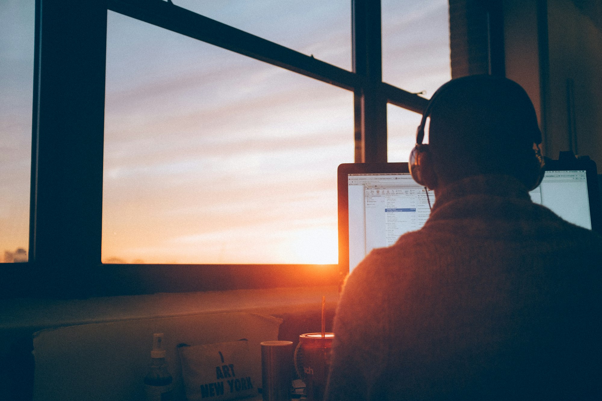 An image of a person working at his computer during sunset