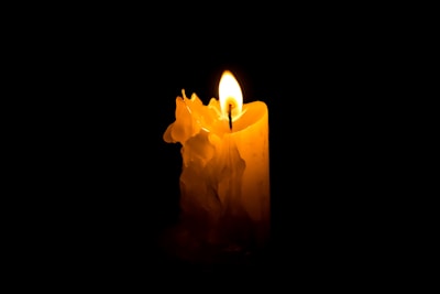 A single candle glowing softly on a windowsill on a snowy evening.