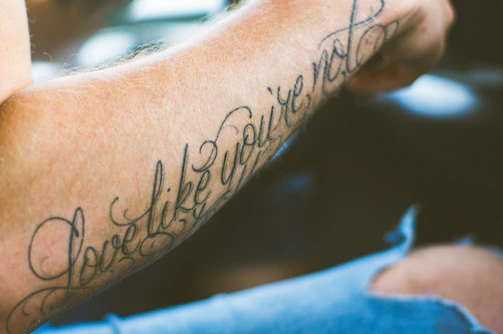 Elegant script tattoo on wrist featuring a meaningful phrase in flowing cursive.