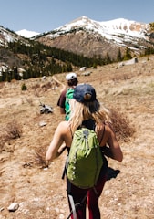 man and woman hiking on brown and white mountain