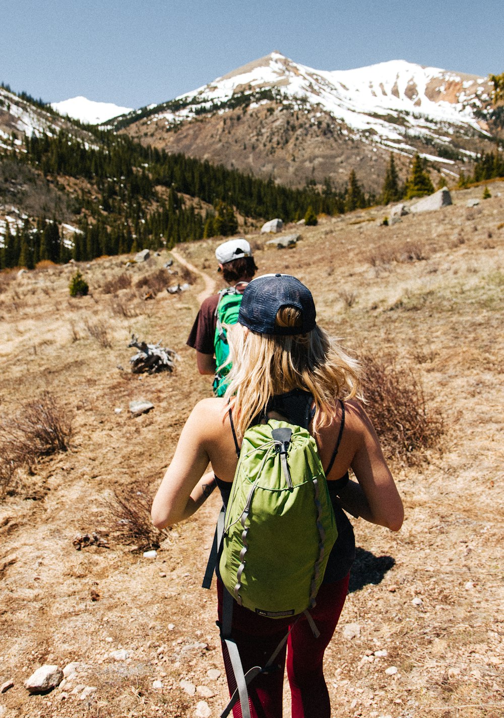 man and woman hiking on brown and white mountain