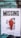 A weathered, torn poster is attached to a brick wall. The poster has the word 'MISSING' in large bold letters at the top. Below it, there is a faded image of a person in a bright red silhouette against a monochrome background. Text at the bottom reads 'IN 50 METERS RADIUS'. The brick wall has a weathered look with green and blue tones.
