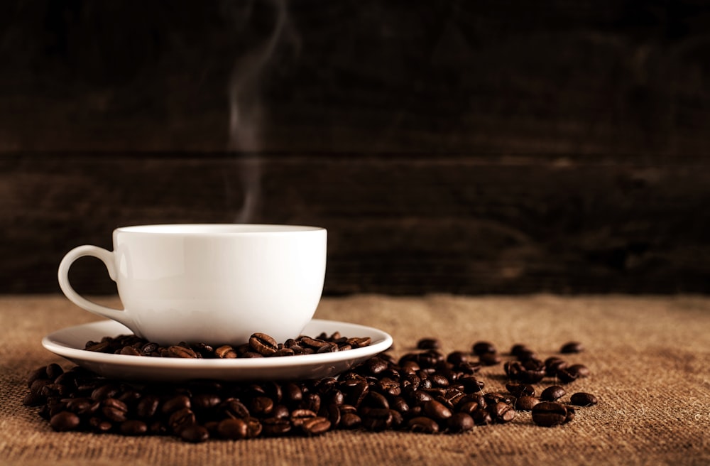 茶色のテキスタイルにコーヒー豆が入った白い陶器のマグカップとソーサー