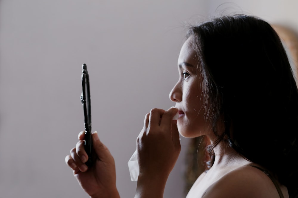 woman looking to mirror and wiping her lips