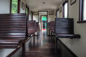 Interior elegant train cabin with polished wood and leather seats, soft natural light filtering through large windows.