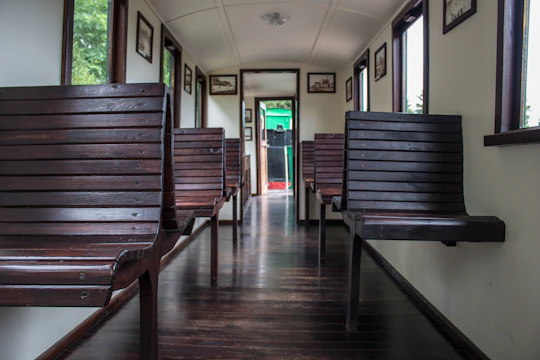Interior elegant train cabin with polished wood and leather seats, soft natural light filtering through large windows.