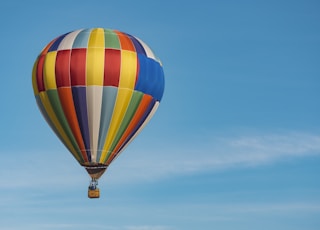 panning photography of flying blue, yellow, and red hot air balloon