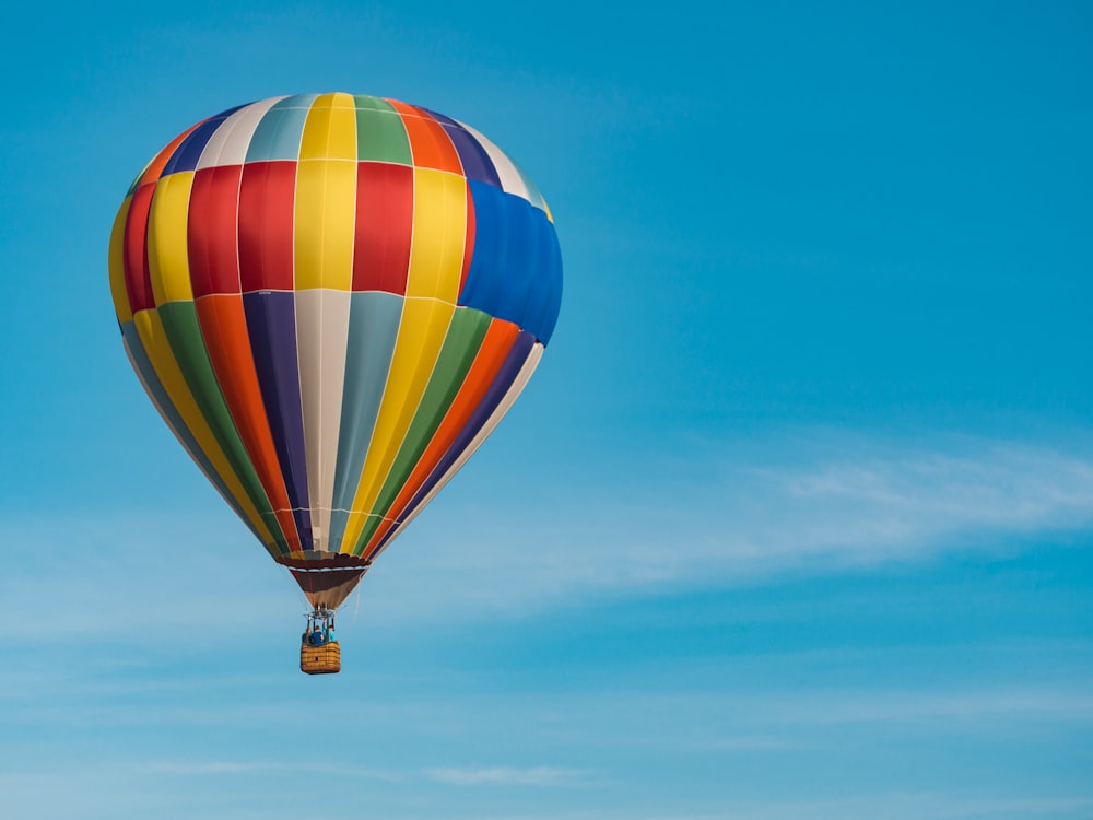 panning photography of flying blue, yellow, and red hot air balloon
