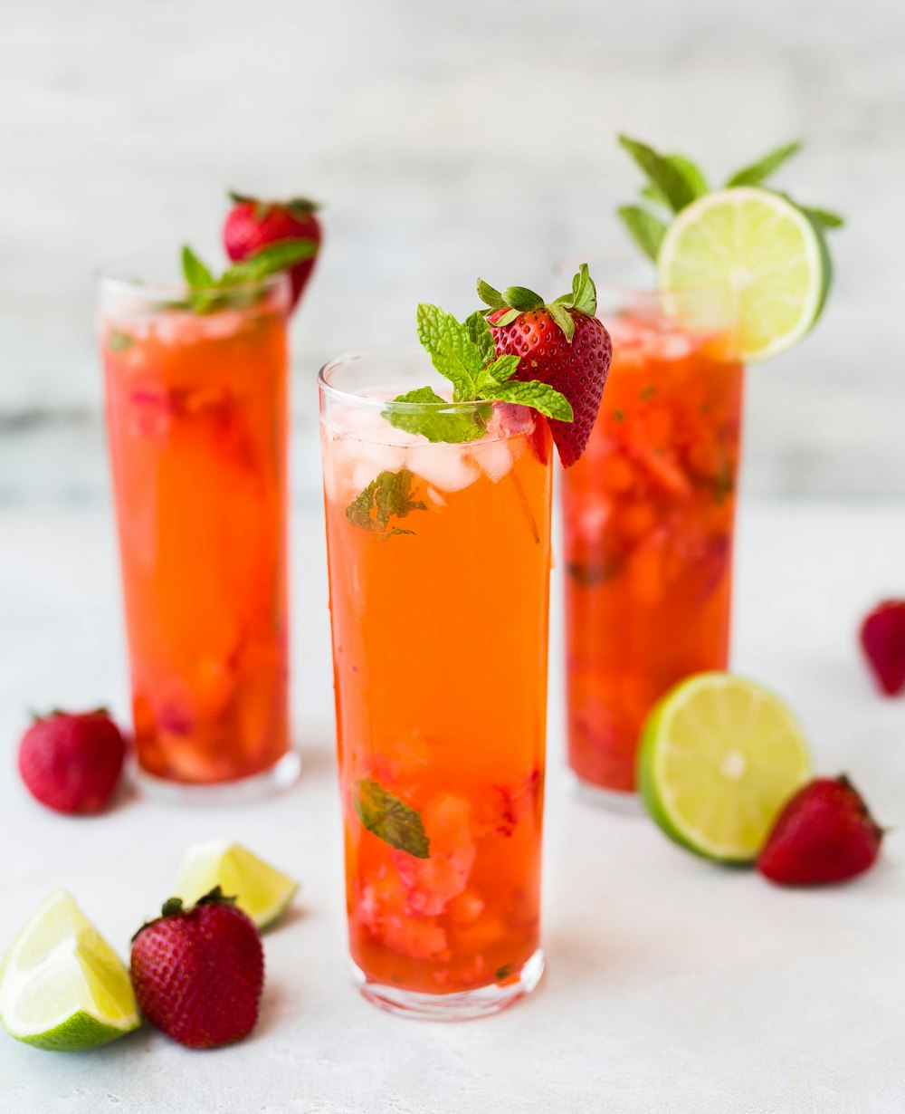 three clear drinking glasses filled with juice