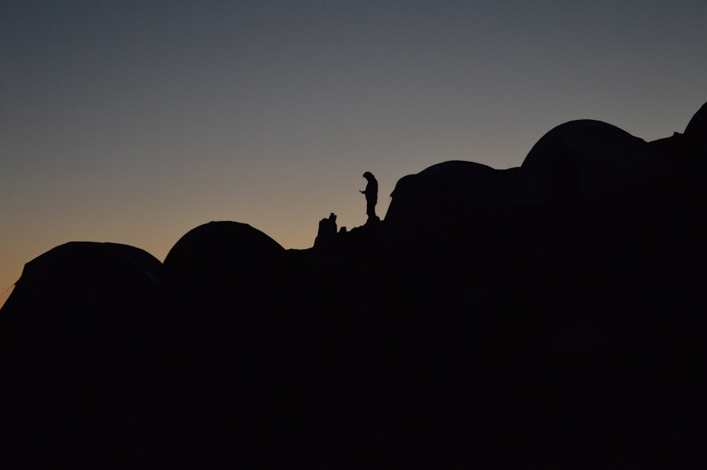 A silhouette of a person in a camping site on a slope at night