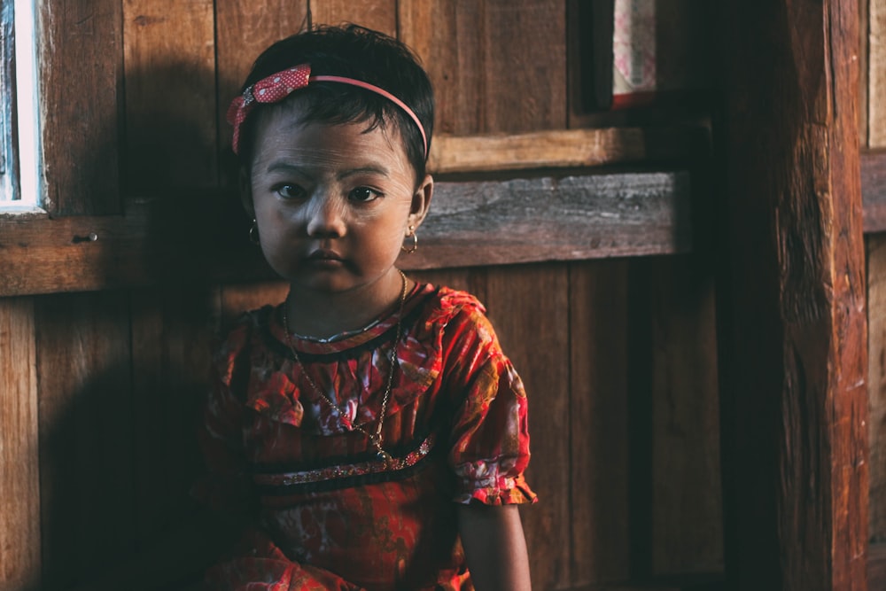 girl standing near brown wooden wall