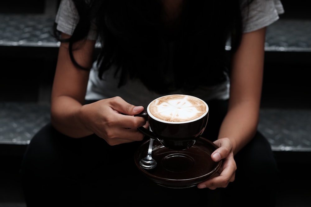 회색 계단에 앉아 접시와 커피 한 잔을 들고 있는 여자