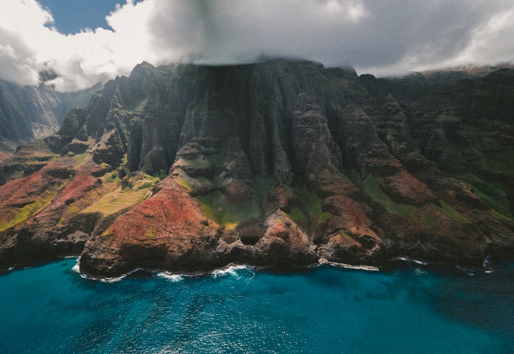 landscape photography of mountain beside body of water under cloudy sky