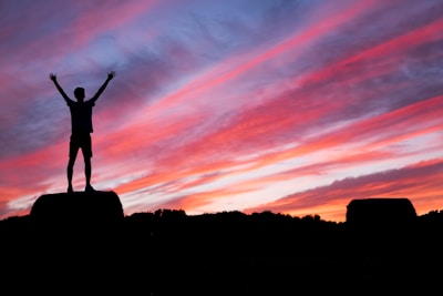 silhouette of man standing on high ground under red and blue skies