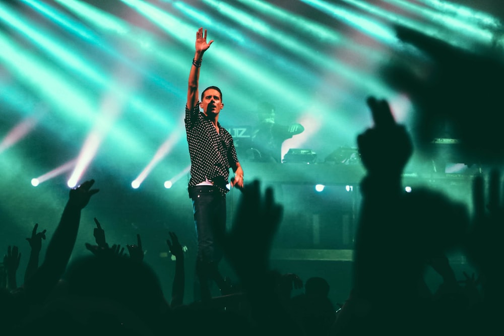 man in black and gray button-up collared shirt standing on stage with green lights turned on