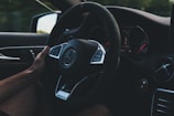 person holding on black steering wheel inside car