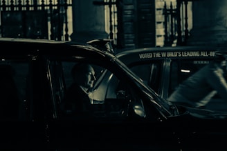 A driver opening the door of a black taxi with warm interior lighting for a night ride.