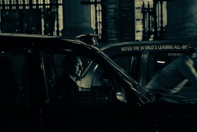 A driver opening the door of a black taxi with warm interior lighting for a night ride.