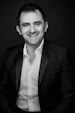 Professional portrait of Francesco Cufone smiling warmly in a modern industrial office setting.