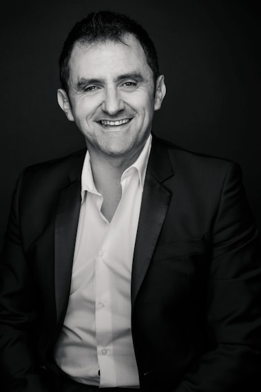 Portrait photo of a board member smiling warmly in a professional setting