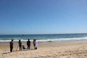 Behind-the-scenes photo of the cast and crew of Sunset Surfer M.D. preparing for a beachside shoot.