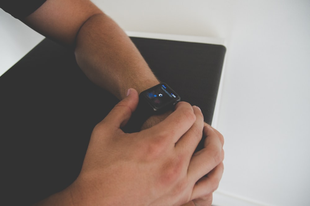 unknown person holding black and blue smartwatch