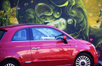 A compact car parked in front of a colorful Tucson mural celebrating local culture.