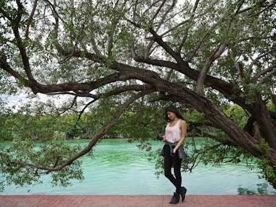 A peaceful outdoor scene with Eroni standing by a tree, looking thoughtfully into the distance