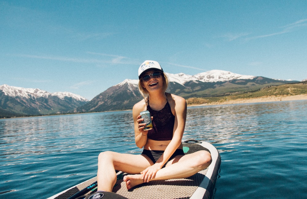 femme portant un crop top noir à col licou assis sur un bateau
