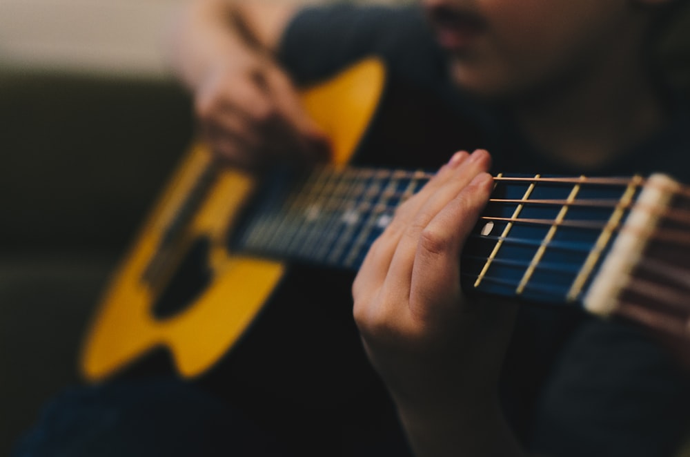 homme assis blanc jouant de la guitare