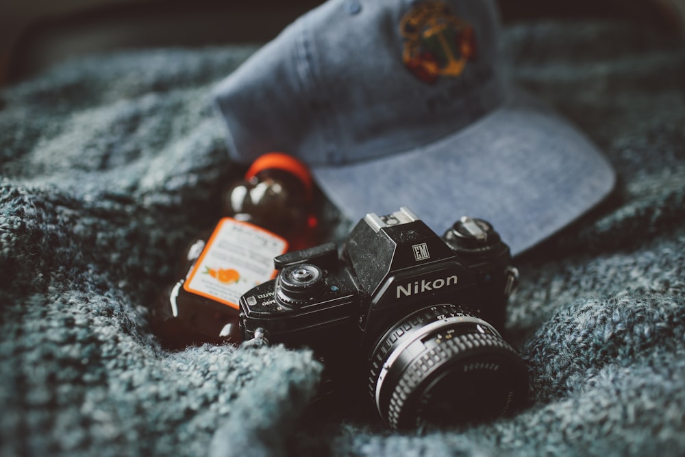 Appareil photo Nikon près d’une bouteille de miel et d’un capuchon bleu sur un textile gris