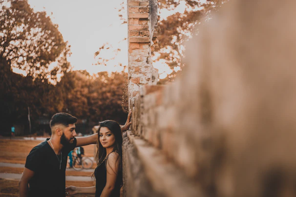 A golden hour capture of a couple exchanging smiles beside rustic terracotta walls.