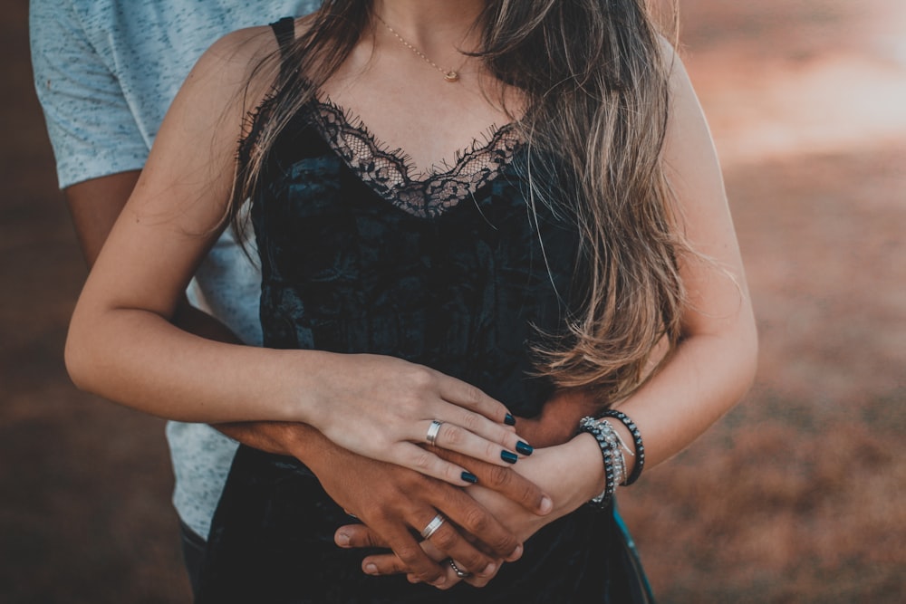 uomo dietro la donna che indossa top in pizzo nero