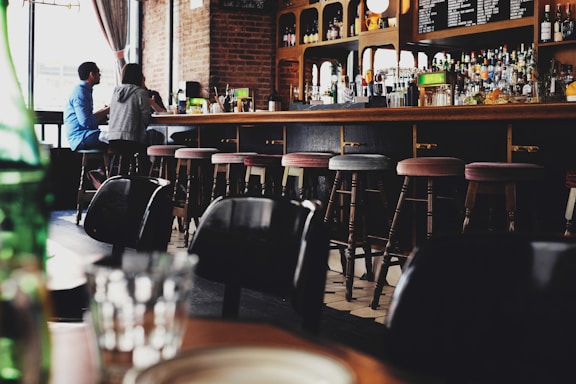 Cozy bar counter with wooden stools and soft lighting in a seafood restaurant.