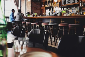 two person sitting on bar stool chair in front of bar front desk