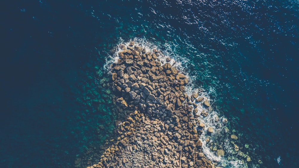 Photographie de vue aérienne de roches brunes au bord de l’océan