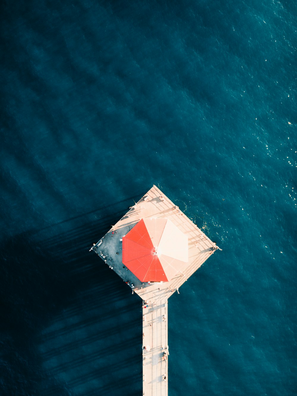 white dock with umbrella on body of water