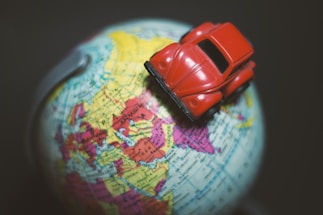 A global map with car icons connecting different continents, symbolizing international vehicle trade.