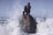 man in black jacket sitting on rock formation in the middle of water