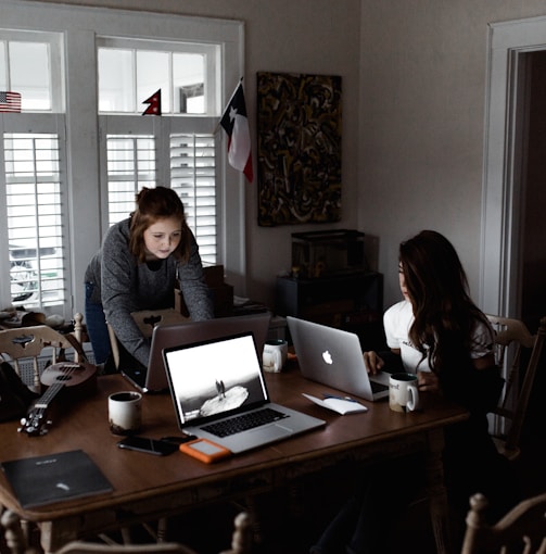 women using laptop on brown wooden table